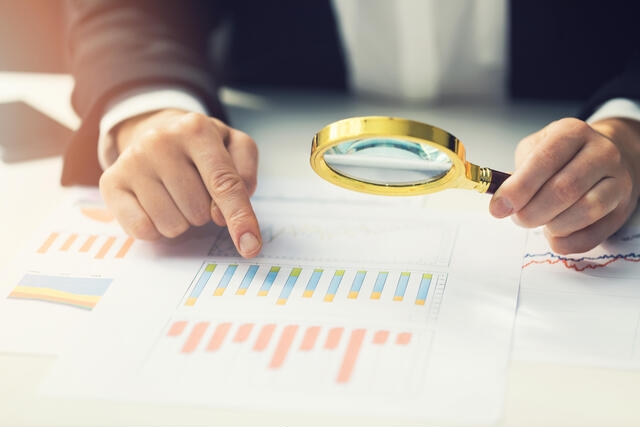 A magnifying glass held over a financial compliance chart