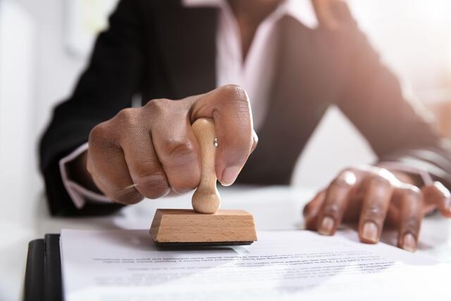 A hand stamping a licence application document