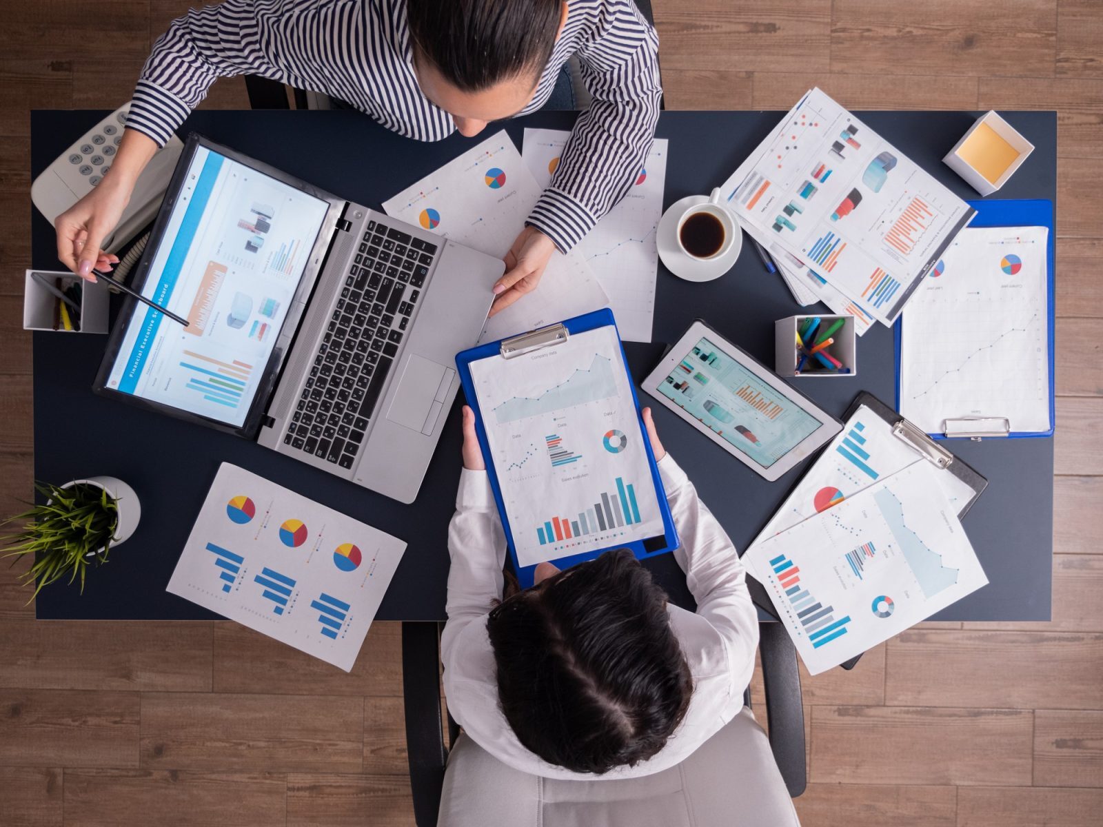 Two analysts reviewing market-entry data and charts at a desk