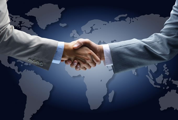 Two business representatives shaking hands over a world map
